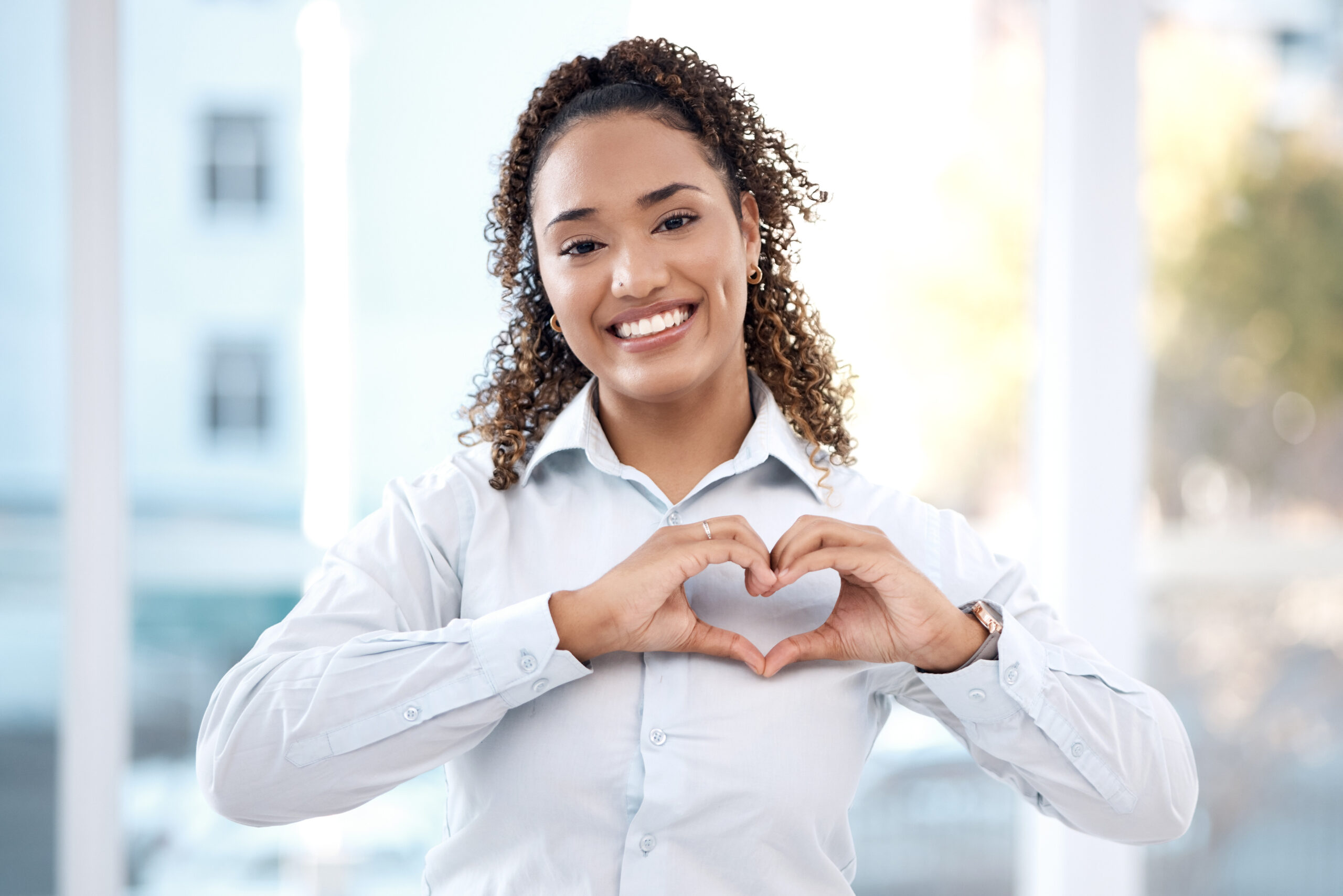 Black woman, hands and portrait with heart emoji for love, charity and support with a happy smile. Face of business person with shape for care, valentines day and hope or sign for review and feedback.